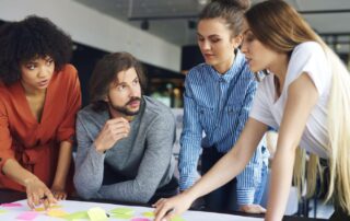 Coworkers discussing ideas written on sticky notes