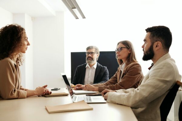 Business meeting with four professionals discussing human resources strategies, emphasizing HR outsourcing and cost management.